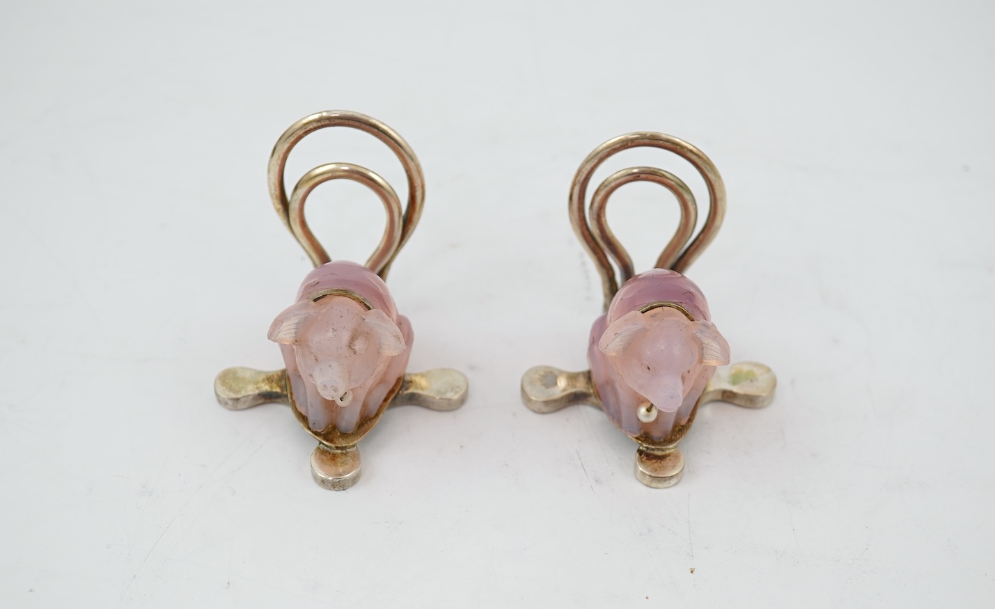 A cased pair of unusual Edwardian silver and pink glass mounted menu holders, by William Comyns, each modelled as a seated pig with collar